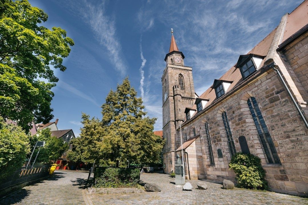 Historischer Kirchplatz mit steinerner Kirche und markantem Turm unter blauem Himmel