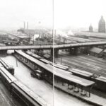 Historischer Bahnhof mit dichtem Gleisfeld, Zügen und Stadtbrücke
